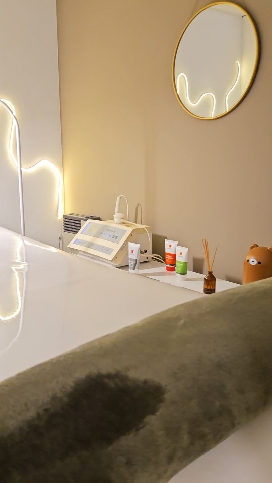 La cabina facial de Depichic: el equipo de electroporación, cremas y un espejo redondo que refleja el neón ondulado