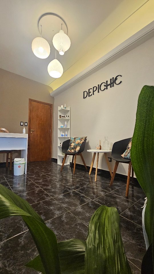 Sala de espera de Depichic: el cartel DEPICHIC en la pared, dos sillas, lámparas colgantes y plantas